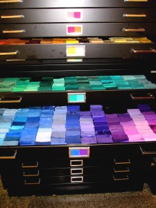 A black filing cabinets with draws opened to show swatches of Munsell color coded fabrics