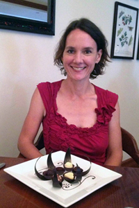 A smiling Kathryn Sampeck sitting in front of a plate of different colored chocolates