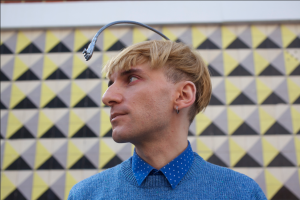 Side view of Neil Harbisson, who hears sound through a camera attached to an antenna on his head.
