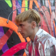 Neil Harbisson pointing the camera attached to his head at a wall mural painting to hear the sounds of the colors.