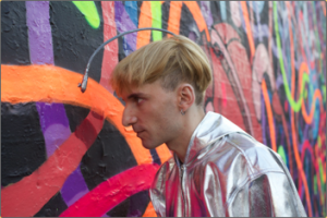 Neil Harbisson pointing the camera attached to his head at a wall mural painting to hear the sounds of the colors.