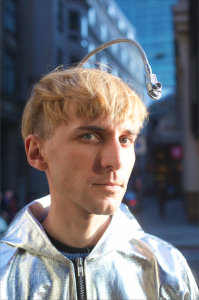 Neil Harbisson, color blind cyborg who hears colors, dressed in silver jacket.