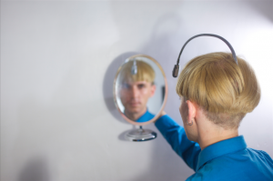 Neil Harbisson, a color blind cyborg who hears colors, viewing himself in a mirror.