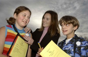 A cancer researcher adjusts a dosimeter on a student while another student looks on