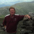 A photo of soil scientist David Wilkinson leaning on a stack of rocks in Acadia National Park in Maine