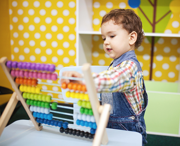 A young boy plays with a colorful counting toy