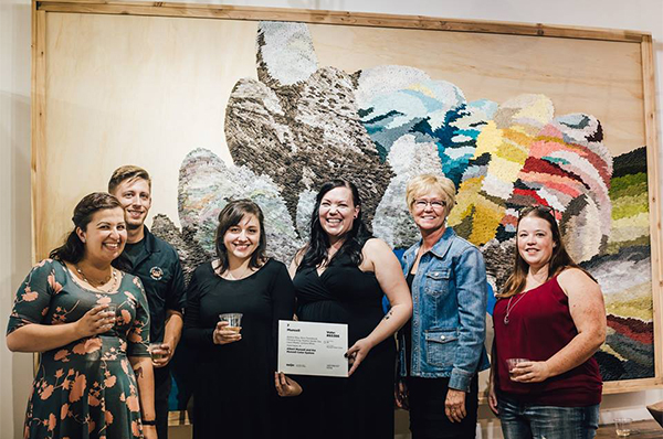 The team from Munsell stands in front of the artwork they created for ArtPrize out of color chips