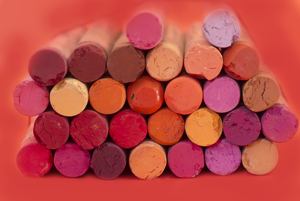 A pile of different colored red crayons