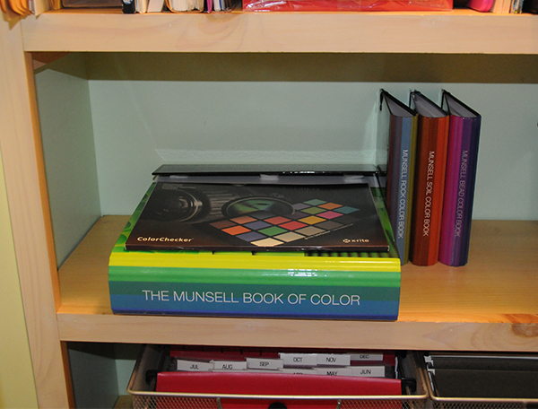 A stack of Munsell color books and charts in a closet being properly stored