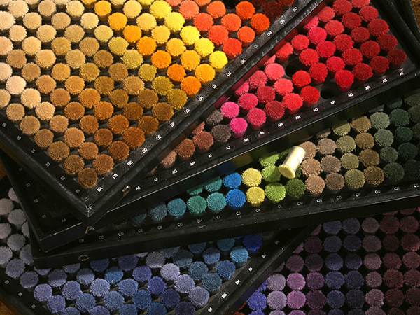 Multiple trays of colored poms used as swatches for dying yard for rugs
